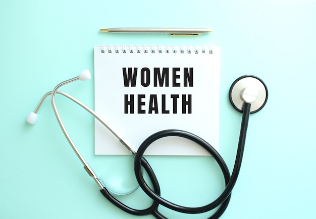 파란색 배경에 WOMEN HEALTH라는 단어와 청진기가 있는 흰색 메모장. 의료 개념