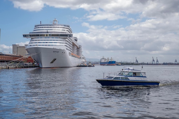 Круизный лайнер по белому океану, синий катер и грузовой корабль в порту на фоне голубого неба