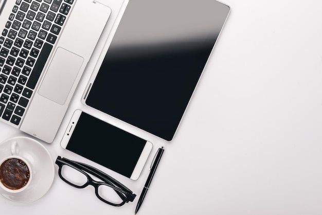 White office desk laptop telefono tazza di caffè occhiali penna matita su sfondo bianco vista dall'alto spazio libero per il testo