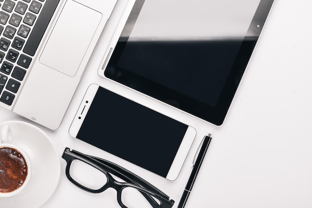 White Office Desk Laptop phone cup of coffee glasses pen pencil On a white background Top view Free space for text