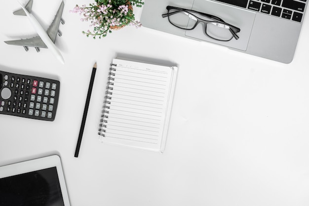 White office desk. table with blank notebook, tablet, calculator, computer and other office supplies