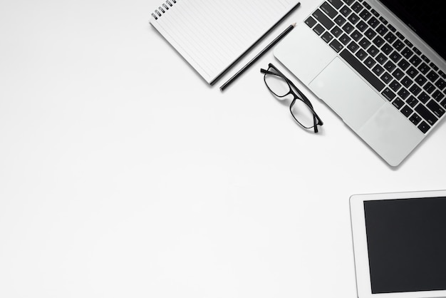 White office desk. table with blank notebook, tablet, glasses, calculator, computer and other office supplies. Top view with copy space.