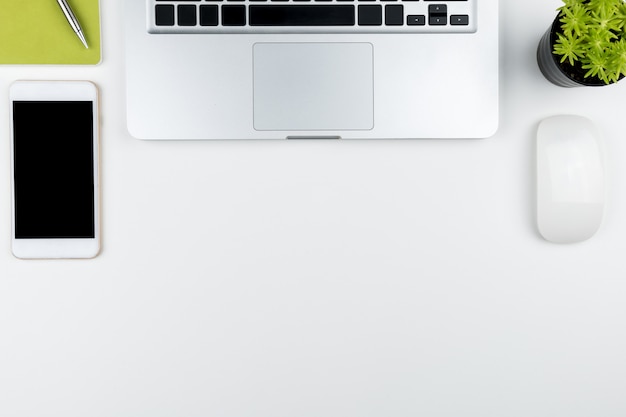 White office desk table with laptop and supplies in flat lay.