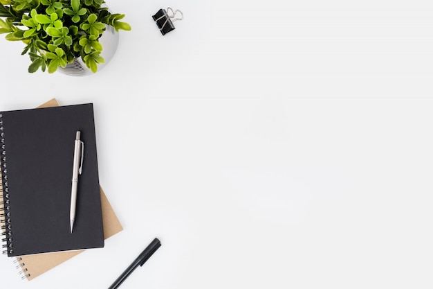 White office desk table with notebooks and pens.