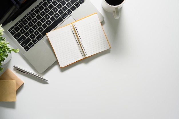 White office desk with laptop notepad and coffee cup Flat lay top view with copy space