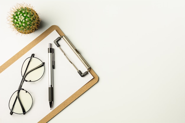 White office desk with a pen and glasses.