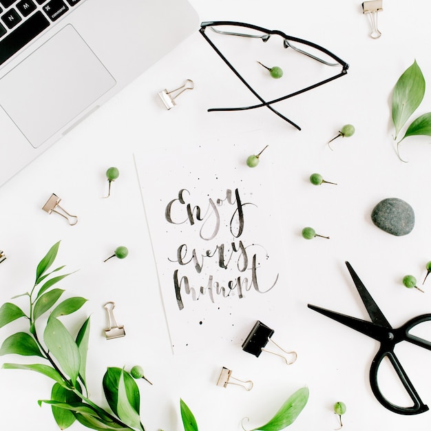 White office desk workspace with paper blank and green leaves