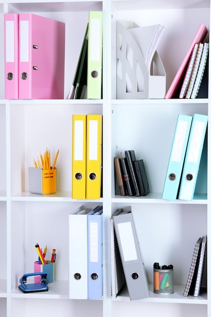 White office shelves with folders and different stationery close up