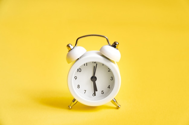 White old alarm clock on yellow 