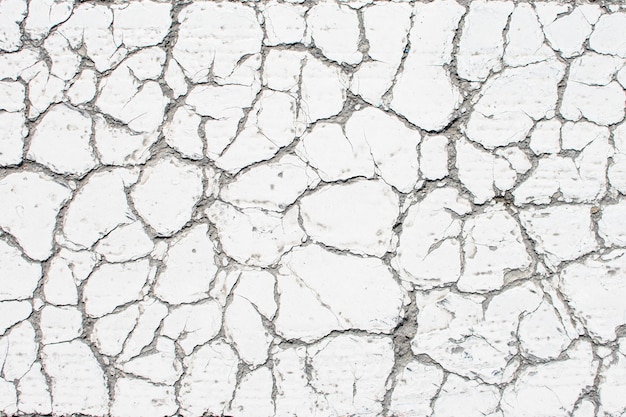 Photo white old cracked paint cracked by the heat in the sun on the concrete surface great for design and texture background