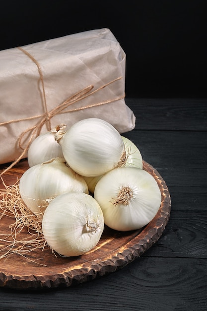 White onions on a wooden board on black background. Organic food