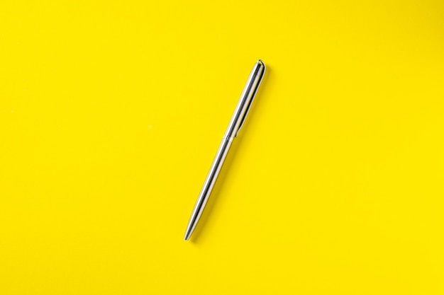 The white open notepad on silver pen isolated on the yellow 
