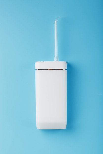 White oral irrigator on a blue surface