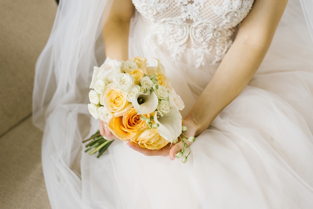 White and orange wedding bouquet in the hands of the bride