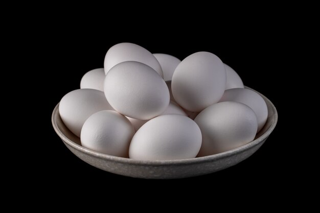 White organic chicken eggs placed in a plate on a black, food