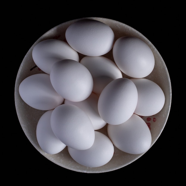 White organic chicken eggs placed in a plate on a black, food