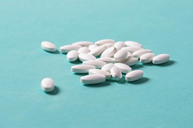 Белые овальные медицинские таблетки на синем фоне Макрофото с копией пространства