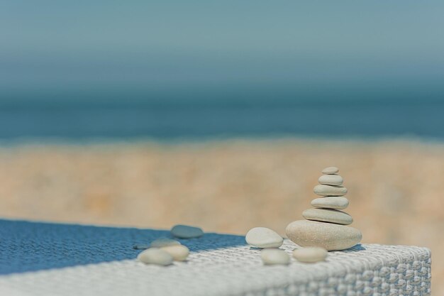 White oval smooth stones lie on top of each other in the form of a pyramid on a sunbed on the beach