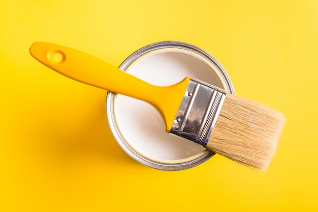 White Paint Can with Brush Top View On Yellow Background