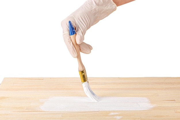 White paint with a brush painting a wooden background with texture