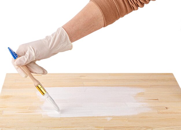 White paint with a brush painting a wooden background with texture