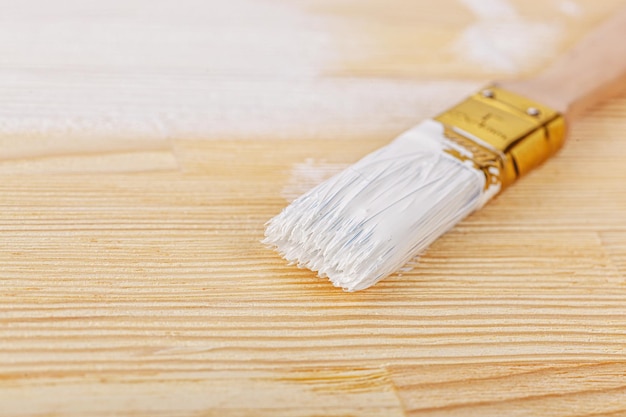 White paint with a brush on a wooden background with texture