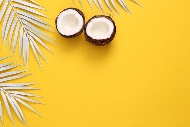 White palm leaves with coconut on yellow background Creative tropical layout Copy space
