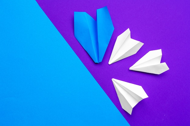 white paper airplane on a blue and purple paper background