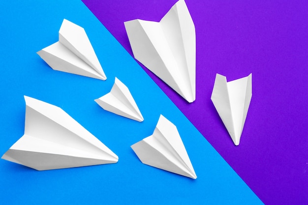 White paper airplane on a blue and purple paper 