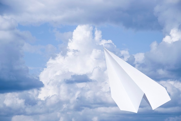 White paper airplane in a blue sky with clouds The message symbol in the messenger