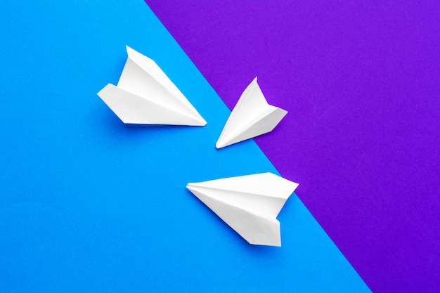 White paper airplane on a color block blue and purple