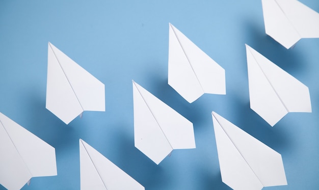 White paper airplanes on blue background.