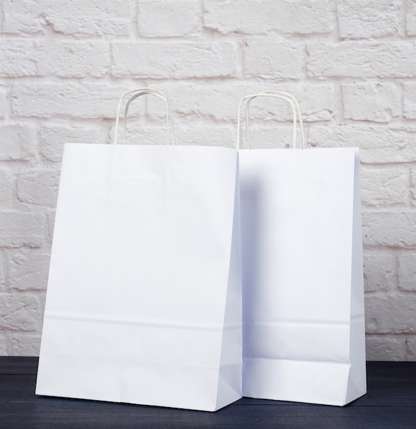 Photo white paper bag with handles on white brick wall