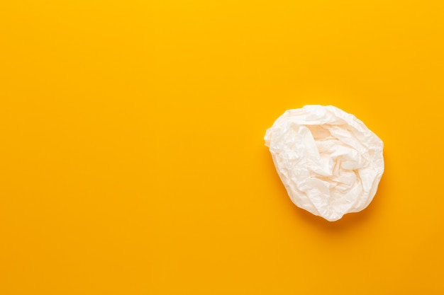 White paper bag on yellow background. Flat lay.