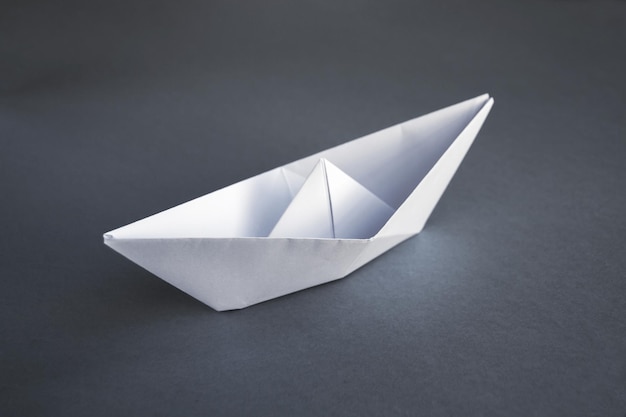 灰色の背景に分離されたホワイトペーパーボート折り紙