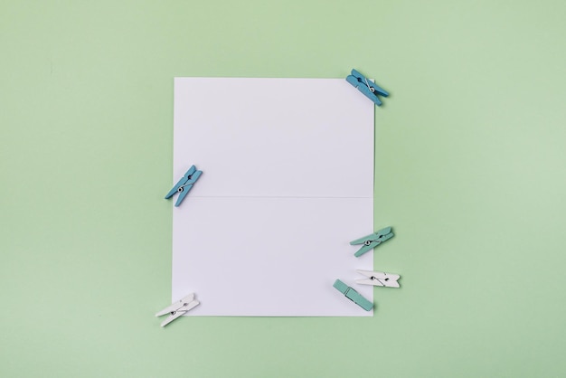 Белая бумажная брошюра с маленькими бело-синими и зелеными булавками на светло-зеленом фоне Макет с белой бумагой Blank Horizontal