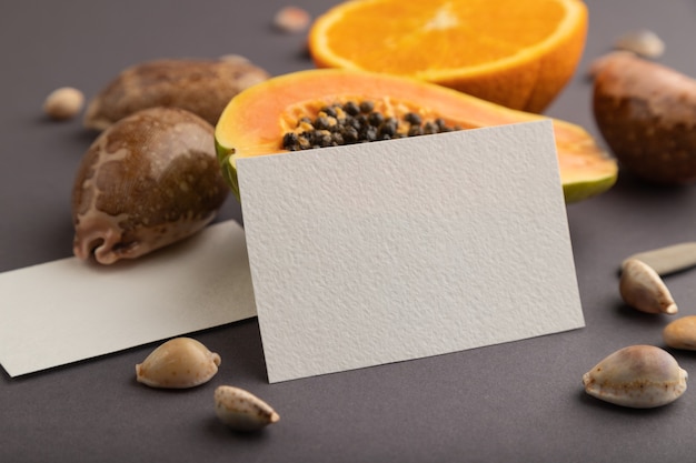 White paper business card with ripe cut papaya, orange, seashells  