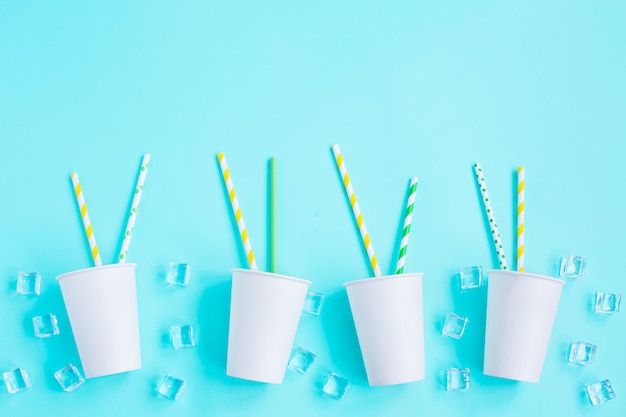 White paper caps with color cocktail straw on blue table.