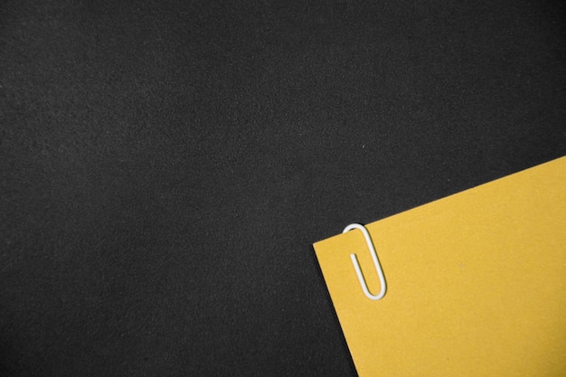 White paper clip with yellow paperwork and reports arranged on black table Space for your text