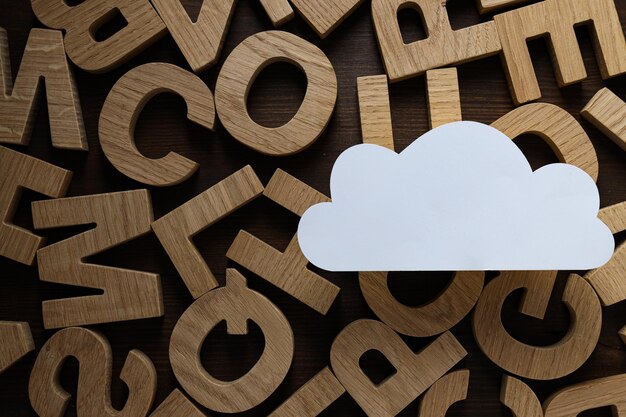 Foto nuvola di carta bianca sullo sfondo di lettere di legno concetto di cloud computing posto per il testo