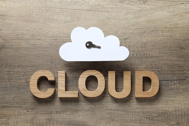 White paper cloud with a key and the word cloud on a wooden background