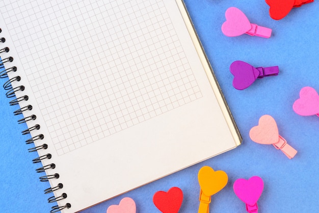 White paper and colored hearts on a blue background. Concept notes for Valentine's Day