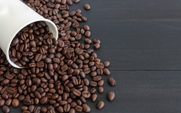 White paper cup and coffee beans on old wooden 