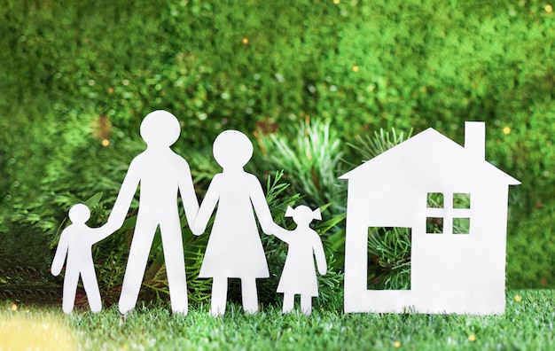 White paper cut of family with house on green grass background