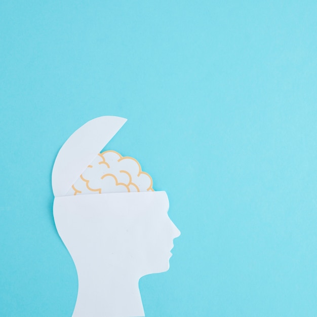 White paper cutout open head with brain on blue backdrop