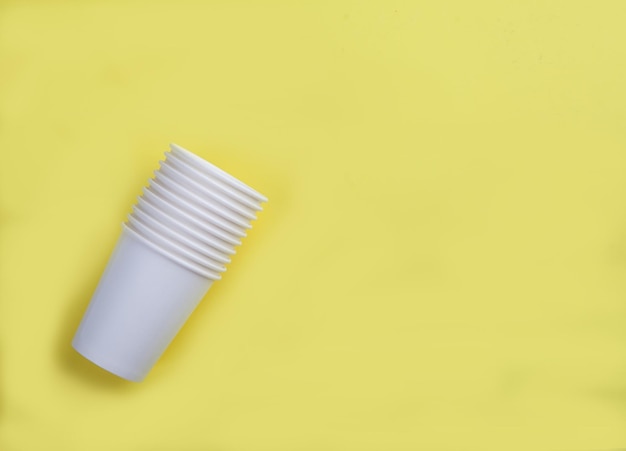 White paper disposable cups on a yellow background View from aboveFlat lay Copy spaes