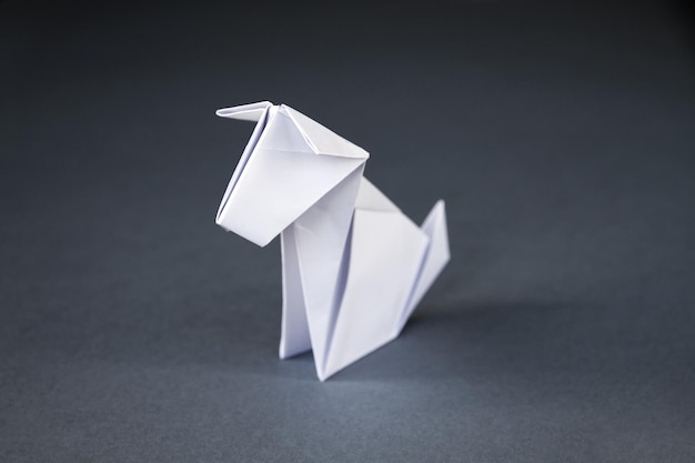 Origami di cane di carta bianca isolato su sfondo grigio