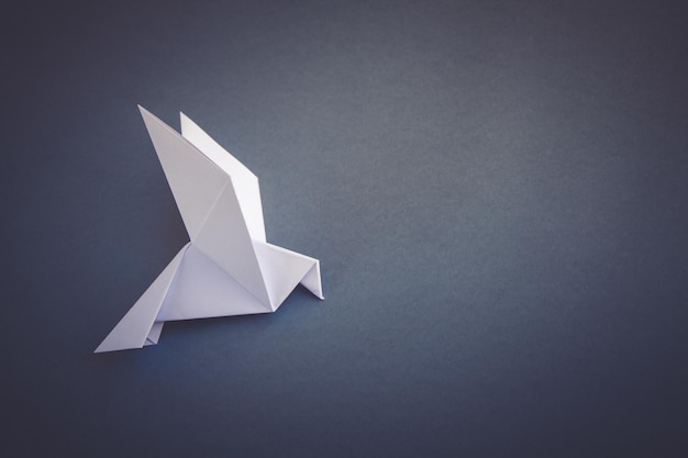 White paper dove origami isolated on a grey background