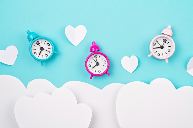 White paper hearts, alarm clocks and clouds. Sainte Valentine, mother's day, birthday greeting cards, invitation, celebration concept