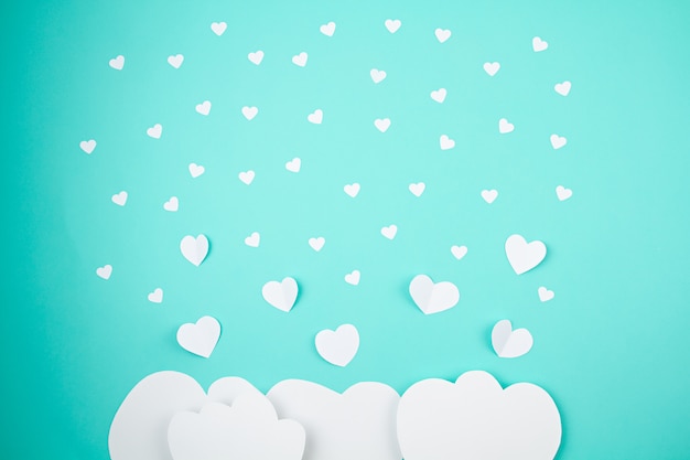 White paper hearts and clouds over the turquoise background